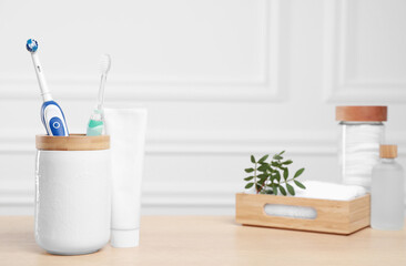 Fototapeta na wymiar Electric toothbrushes, tube of paste and toiletries on wooden table