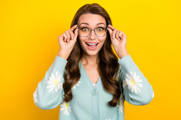Portrait of young surprised astonished funny girl hold her eyeglasses surprised good vision stylish spectacles isolated on yellow color background