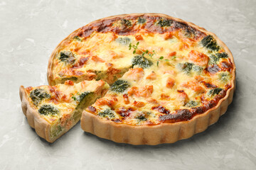 Delicious homemade quiche with salmon and broccoli on light gray table
