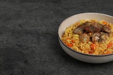 Obraz na płótnie Canvas Delicious pilaf with meat on grey textured table, space for text