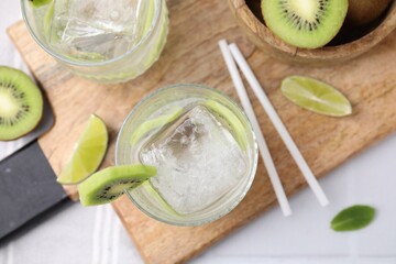 Refreshing drink, cut kiwi and lime on white table, flat lay