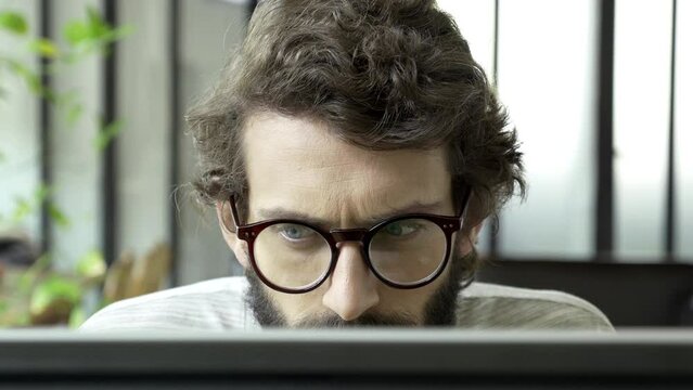 Man face is concerned, interested, strained. He is looking to the screen and reading very fast. Information is interesting and shocking, the reader also very curious and focused.