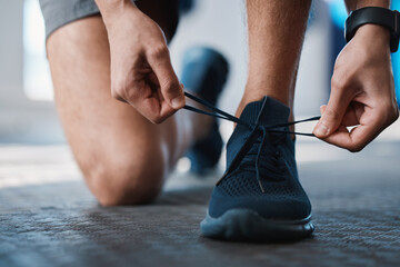 Fitness, shoes and tie with a sports man in the gym getting ready for a cardio or endurance workout. Exercise, running and preparation with laces of a male athlete or runner at the start of training