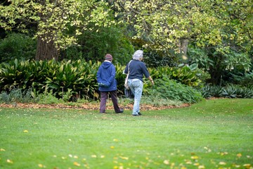 couple walking in a garden. man and woman walk in nature under trees surrounded by plants. family together in a park in spring time