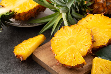 Fresh cut sliced pineapple in a plate over dark gray table background.