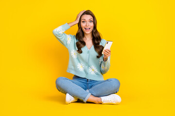 Obraz na płótnie Canvas Full length photo of shiny impressed lady dressed teal cardigan communicating modern gadget isolated yellow color background