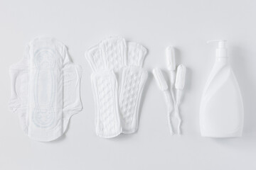 Tampons, feminine cotton sanitary pads and liquid intimate soap on a white background