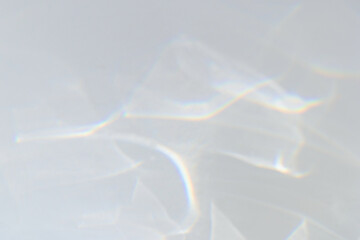 Blurred water shadows and light refraction texture overlay effect for photo and mockups. Organic drop diagonal holographic flare on a white wall. Dreamy surreal rainbow for natural light effects