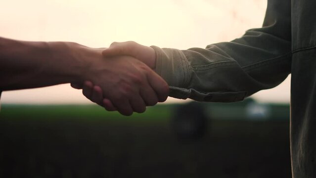 farmers handshake business contract. two farmers at sunset with a corn irrigation plant in the background shaking hands. agriculture irrigation business concept. farmers handshake lifestyle