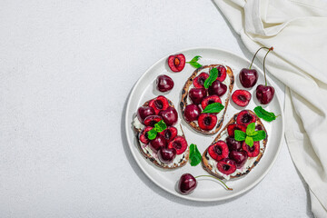 Fresh bread sandwiches with sweet cherry, cream cheese and mint leaves. Morning breakfast concept