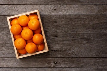 Orange fruit  in wooden crate isolated on wooden table background, top view, flat lay, copy space. 