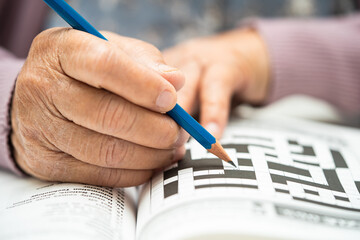 Alzheimer disease AD, Asian elderly woman playing sudoku puzzle game to practice brain training for dementia prevention.