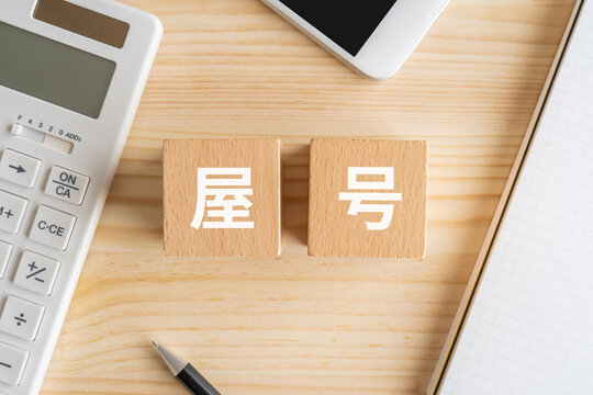 屋号と書かれたブロック、電卓、スマホ、ノート