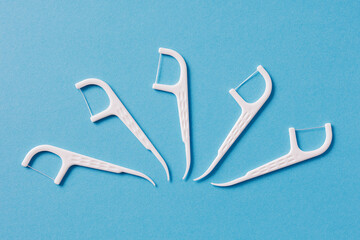 Many white dental toothpicks with dental floss on blue