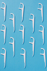 Pattern of dental floss with a plastic toothpick on blue background