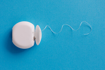White dental floss for cleaning teeth on blue