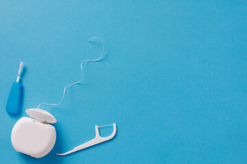 Dental floss and toothpicks on blue background