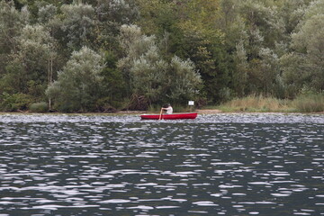 Fototapeta premium Photo of a man peacefully rowing a small boat on a lake, Austria