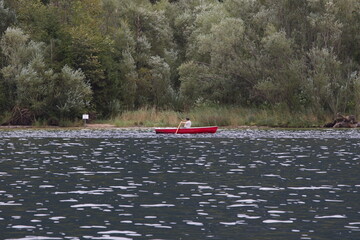 Photo of a man peacefully rowing a small boat on a lake, Austria