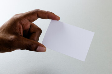 Hand of biracial man holding white business card with copy space on white background