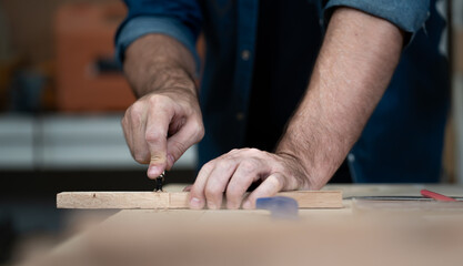 Male carpenter working with skill in carpentry workshop. Professional joiner works with tools in woodworking. Closeup of mature woodworker making or repairing furniture. Craftsmanship industry