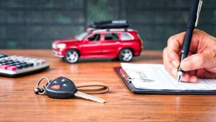 Car loan or buying a new car concept. Car key on table with a man signing on leasing or document  form and red car in background. Leasing and insurance business. - obrazy, fototapety, plakaty