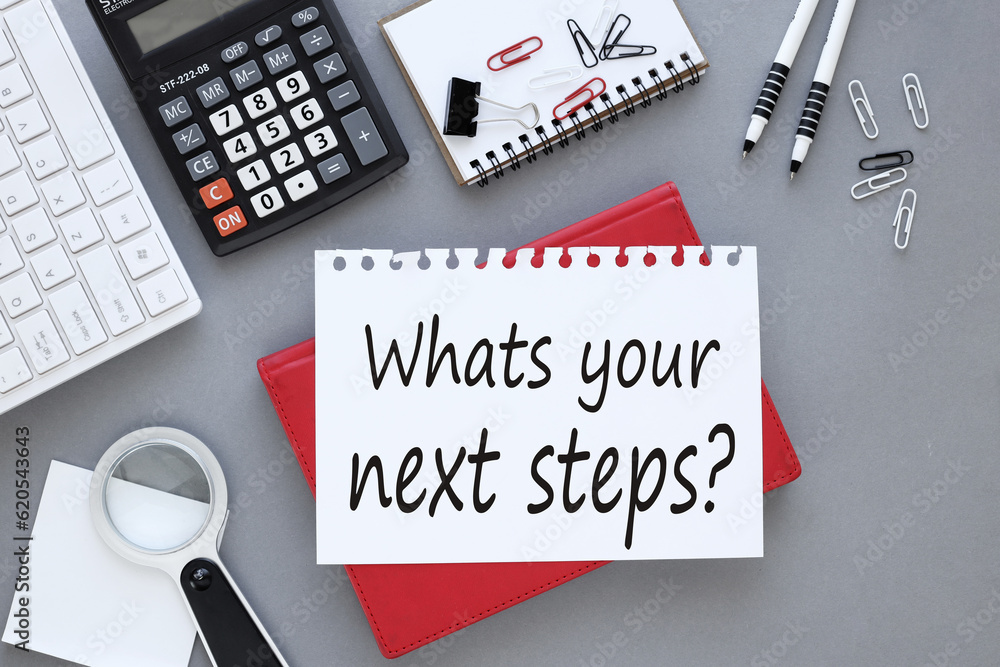 Poster what's your next step? white sheet of paper with text. on a red notepad on a gray background near a 