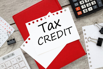 tax credit . Business concept. white sheet of paper with text. on a red notebook