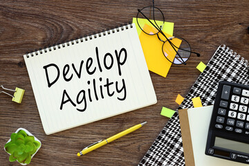 develop Agile text. Notepad, white sticker and pensil on the desk.