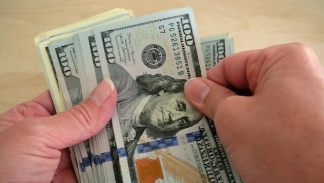 Hand holding big stack of dollar USA money on wooden background. money cash,