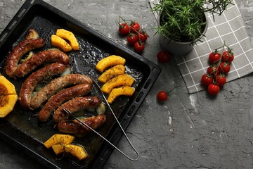 Homemade sausages and pumpkin baked on a metal grill