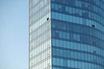 Fototapeta na wymiar Part of a glass mirrored office building reflecting the blue sky.
