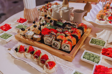 Big buffet reception of different delicious food at a wedding celebration. Snacks for guests. Wedding party. Canapes, sushi, fruit, meat, drink, wine, juice.