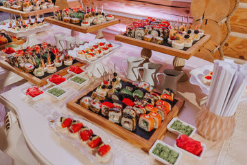 Big buffet reception of different delicious food at a wedding celebration. Snacks for guests. Wedding party. Canapes, sushi, fruit, meat, drink, wine, juice.