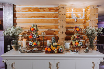 table with various fruit decorations. Watermelon carving, pineapple slices, grapes, orange