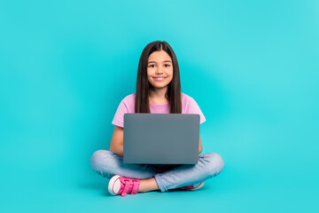 Naklejka premium Full body size photo of cheerful preteen girl writing essay computer netbook education literature isolated on aquamarine color background