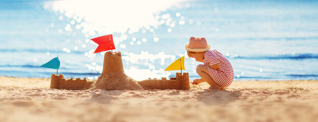 Little boy building sand castle on the sea beach.