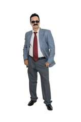 Mature indian businessman wearing suit and sunglasses standing with his hands in pocket isolated over white background. Corporate Concept.