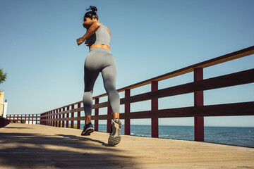 beautiful brunette girl in gray leggings runs on the seashore