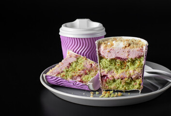 Takeway cake in a glass with pistachios, strawberry mousse and strawberry confit on gray plate on black background