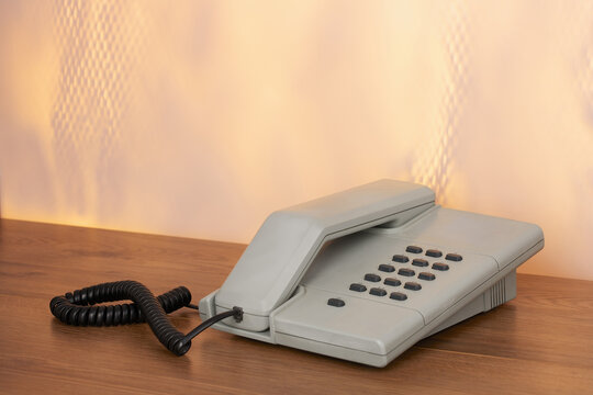 Vintage grey telephone on wooden desk colorful background
