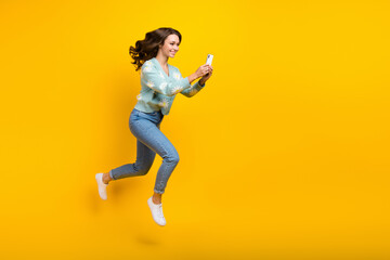 Full length body photo of young good mood run fast speed girl blogger wavy brown hairdo recording phone new video isolated on yellow color background