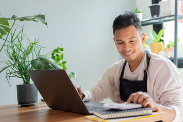 close up young business owner of plant shop press calculator while sit in the room to checking about investing and order and marketing for startup and business lifestyle concept