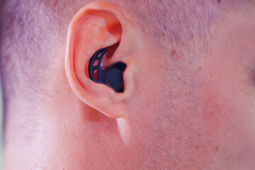 black waterproof earplugs in the man's ears.