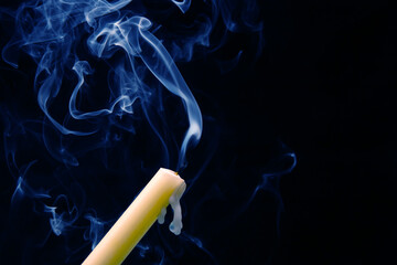 Smoke from an extinguished candle on a dark background. The concept of spirituality and the end of...
