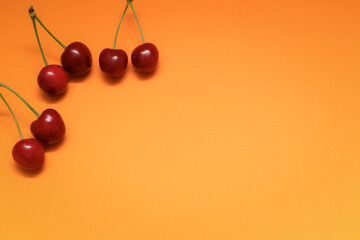 Concept of fresh summer food - delicious cherry. Red sweet cherry berry on a orange background