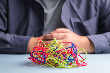 Colorful tangled ropes on the table in front of a man, psychological problem, confused situation