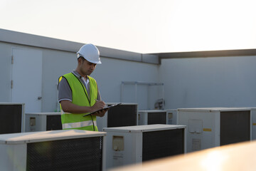 Asian maintenance engineer works on the roof of factory. contractor inspect compressor system and plans installation of air condition systems in construction. Checklist, inspector, control.