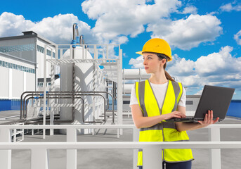 Woman in industrial plant. Factory worker with laptop. Woman engineer uses computer. Worker near modern factory. Girl in vest and helmet. Tanks with mezzanine behind specialist. Chemical factory