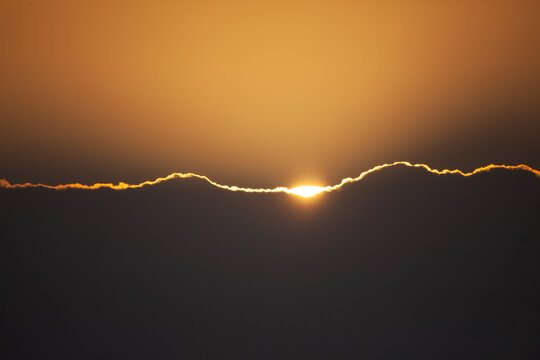 Close image of sunset sun rising over clouds. 